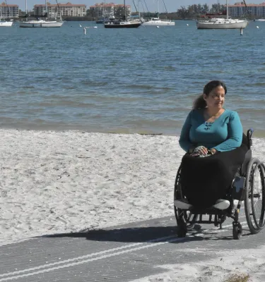 Woman in wheelchair on mat on the beach