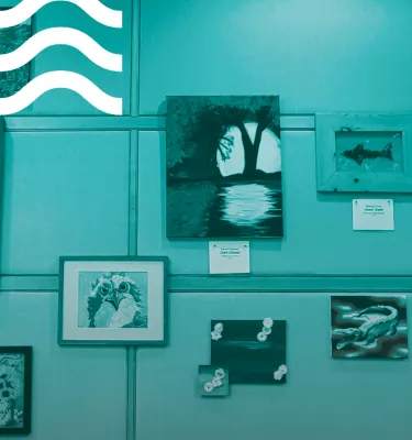 Teal photo of the inside of an art gallery featuring various works of art.