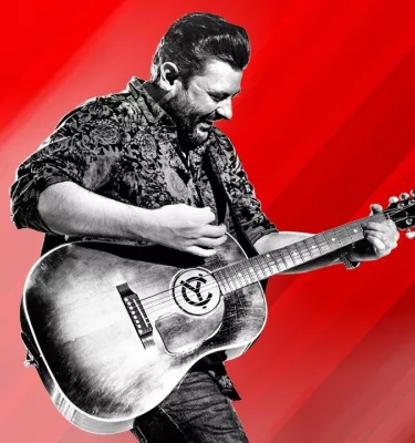 Musician Chris Young playing an acoustic guitar in front of a red background.