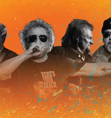 Sammy Hagar and his band performing in front of an orange background.