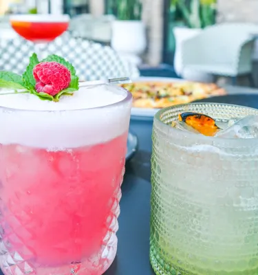 a frothy pink cocktail with a raspberry and a mint leaf next to another cocktail at the Sonder Social Club in Dunedin