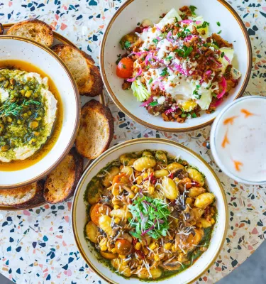 Three dishes of vegan food on a speckled table
