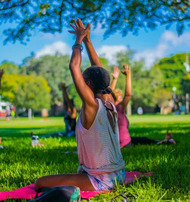 A group of ladies doing a yoga pose on the grass during the daytime.