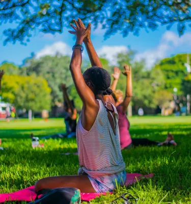 A group of ladies doing a yoga pose on the grass during the daytime.