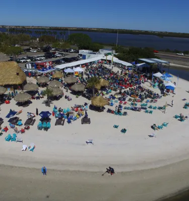 Aerial photo of a restaurant on the bay with groups of people mingling. 