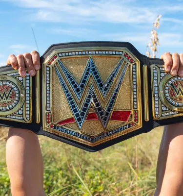 Cropped shot of arms and hands holding the massive WWE belt on the beach