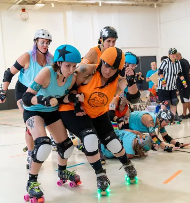 Photo of an indoor roller derby tournament featuring multiple women on skates.