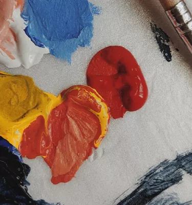 Zoomed-in image of paint colors on a paint palette featuring paint brushes.