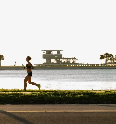 a runner near Tampa Bay with the St. Pete Pier in the background