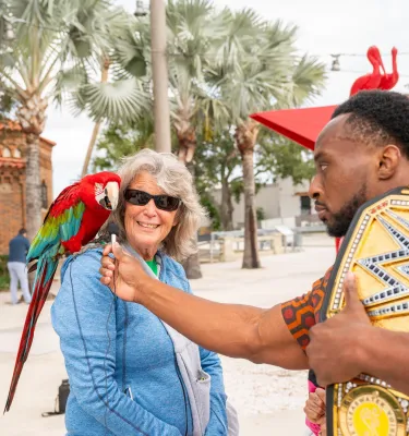 woman with a parrot on her shoulder talks to a wwe wrestler