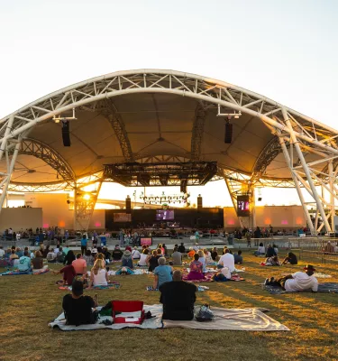 people on blankets on the lawn near a curving outdoor amphitheater called The Sound at Coachman Park in Clearwater
