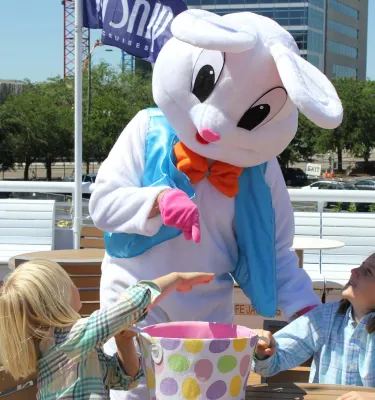 Easter bunny costume character playing with kids onboard a yacht dining cruise.