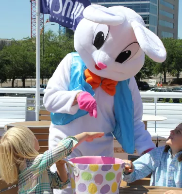 Easter bunny costume character playing with kids onboard a yacht dining cruise.