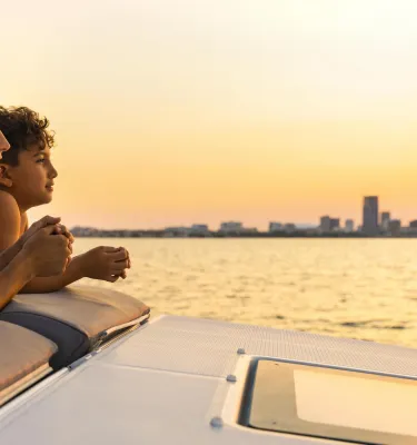 a woman and a young boy relax on the deck of a boat to watch the sunset