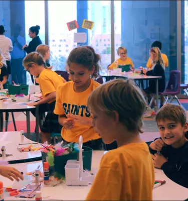 Kids in a classroom setting making arts and crafts.