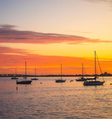 a brilliant orange and yellow sunset with sailboats anchored in the bay in Gulfport