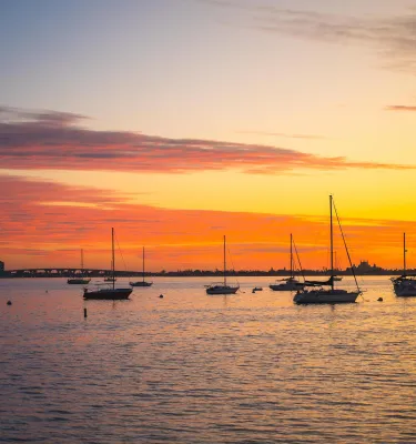 a brilliant orange and yellow sunset with sailboats anchored in the bay in Gulfport