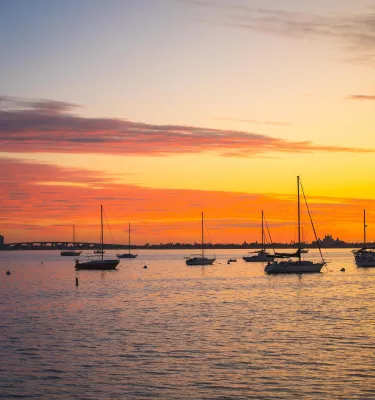 a brilliant orange and yellow sunset with sailboats anchored in the bay in Gulfport