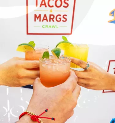 Three people cheers-ing with margaritas.