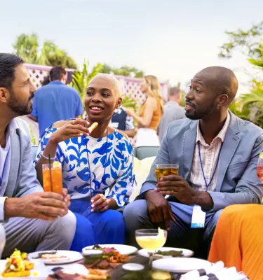 four people gather around a table outside for food while attending a meeting