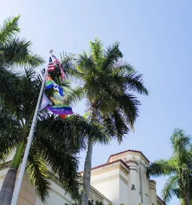 Flag pole outside City Hall in St. Pete during the daytime featuring the city flags and the Pride flag.