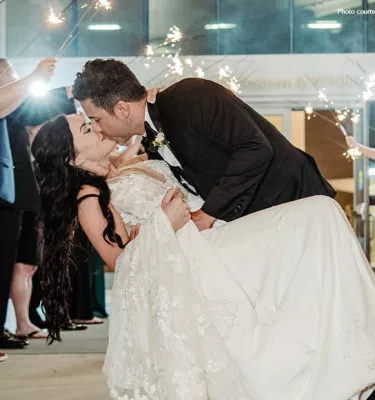 Wedding couple kissing in front of a crowd.