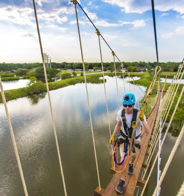 A man walks on a suspended bridge at Empower Adventures