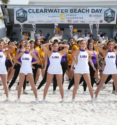 Cheerleaders doing a cheer dance on Clearwater Beach during the day.