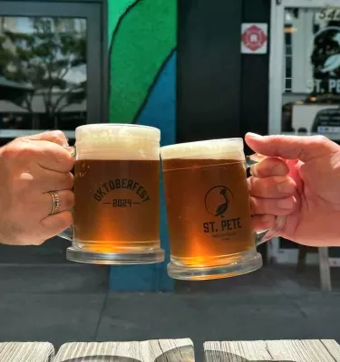 Two people doing a cheers with pints of beer.