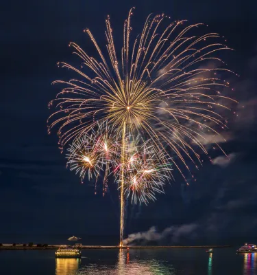 Fireworks exploding in the sky over water.