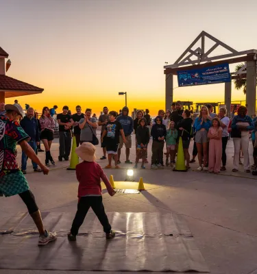 a performer engages with a small child at the sunsets at Pier 60 nightly celebration