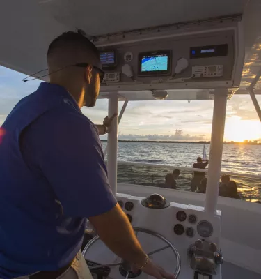 A boat captain steers along the water