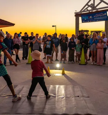 a performer engages with a small child at the sunsets at Pier 60 nightly celebration