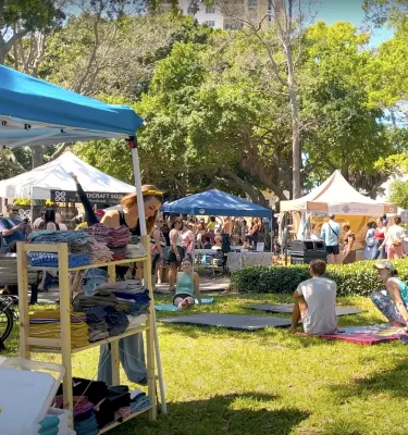 Outdoor festival featuring people shopping at vendor tents and people hanging out and sitting on the grass.