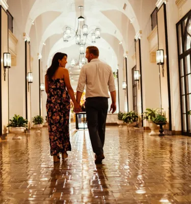 a woman and a man walk down a shiny tiled hallway with arched ceilings at the Vinoy Resort & Golf Club