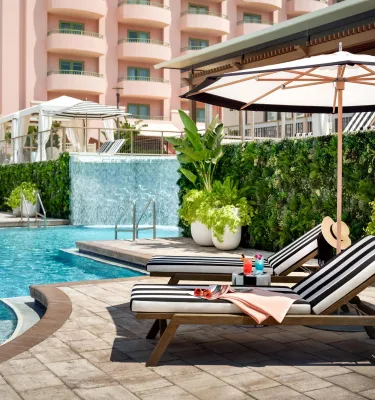two striped lounge chairs sitting next to Vinoy pool with waterfall feature in background