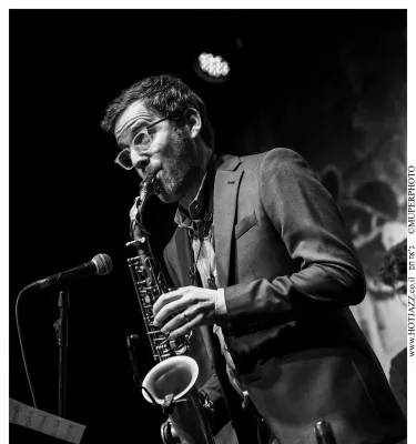 Black and white photo of a man playing the saxophone on stage.
