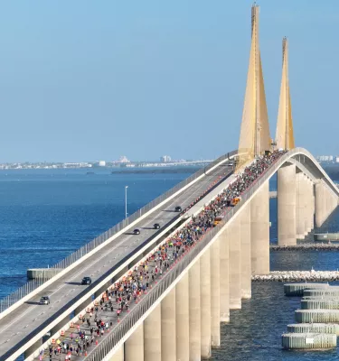 Aerial photo of the Sunshine Skyway Bridge featuring blue water and people running on the bridge.