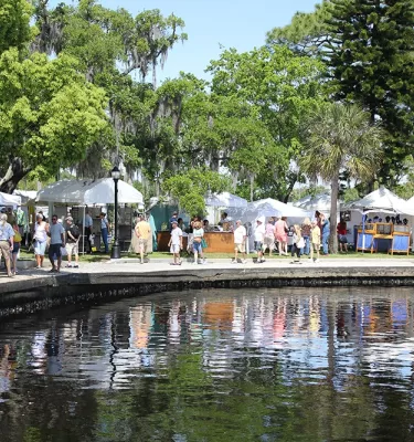 Outdoor arts festival on the water in Tarpon Springs featuring people shopping at multiple vendor tents.