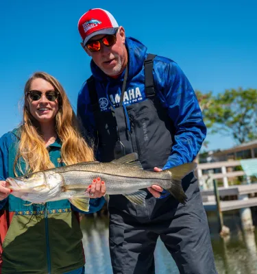 A woman and a captain hold up a snook for a picture