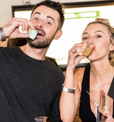 A couple posing for a photo and sipping margarita drinks.
