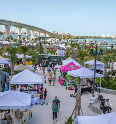 Outdoor market featuring multiple vendor tents and shoppers.