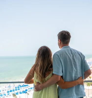 A couple looks out at the balcony of a beachfront resort