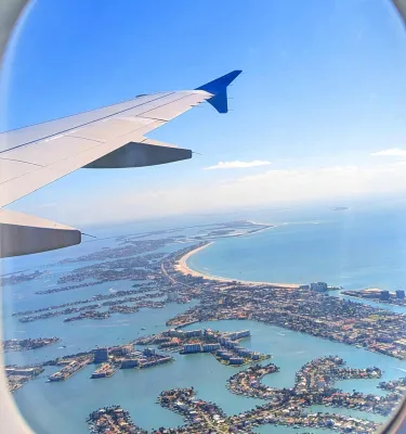 a view out the window of a plane with water and land visible below as well as the plane's wing