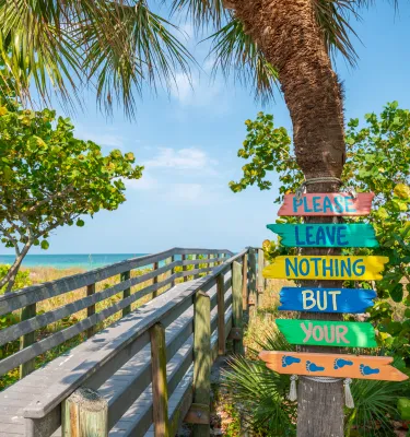 boardwalk bridge to the beach with a sign that says "please leave nothing but your footprints"