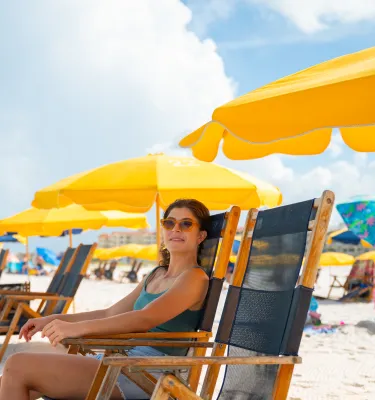 a woman relaxes in a beach chair under a yellow umbrella at Palm Pavilion Inn on Clearwater Beach