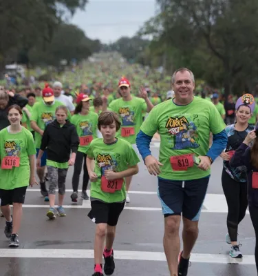 People in green t-shirts running in a Turkey Trot race outside.