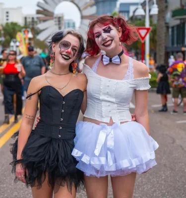 two women dressed up in costumes with a crowd of people behind them at the Halloween on Central event in St. Petersburg FL