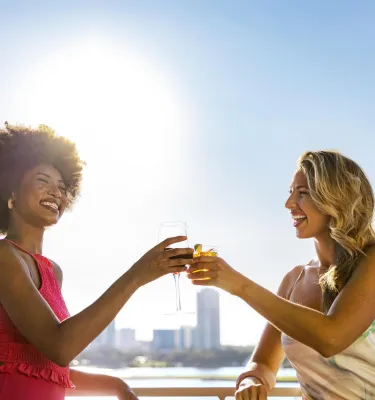 two women toast with cocktails at Pier Teaki rooftop bar at the St. Pete Pier