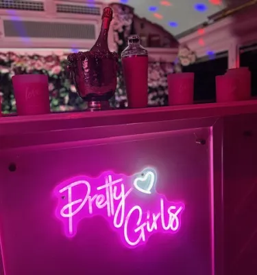 a pink bar with a neon sign that says "Pretty Girls" inside the Pink Bus run by Star Trolley